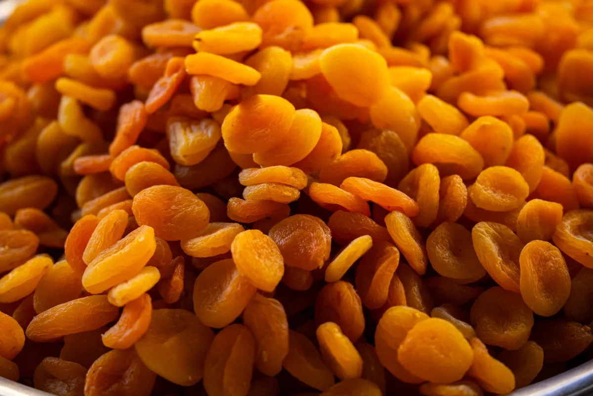 Mains tenant un sachet d'abricots secs ouvert, liste des ingrédients et tableau nutritionnel lisibles au dos
