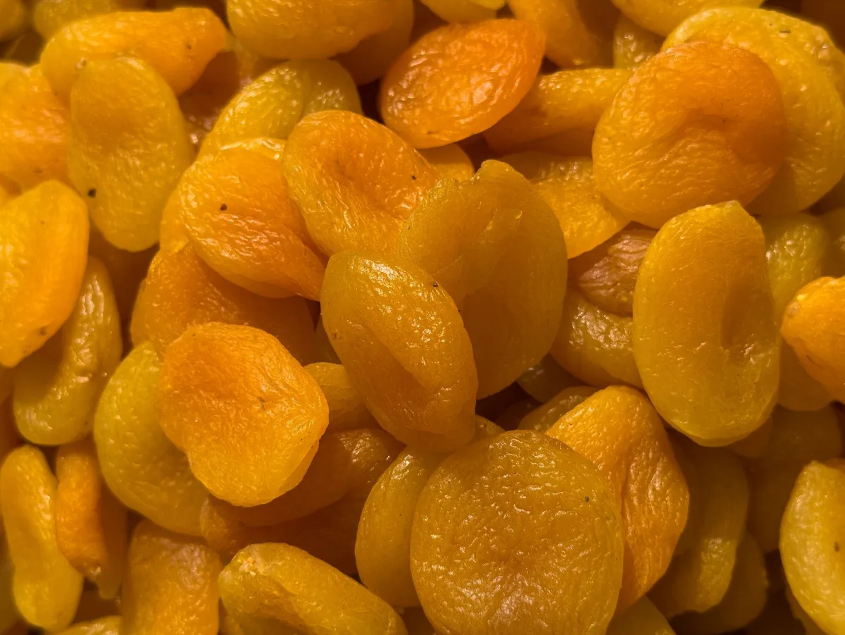 Abricots secs orange vif et abricots secs bruns présentés côte à côte dans deux coupelles en céramique