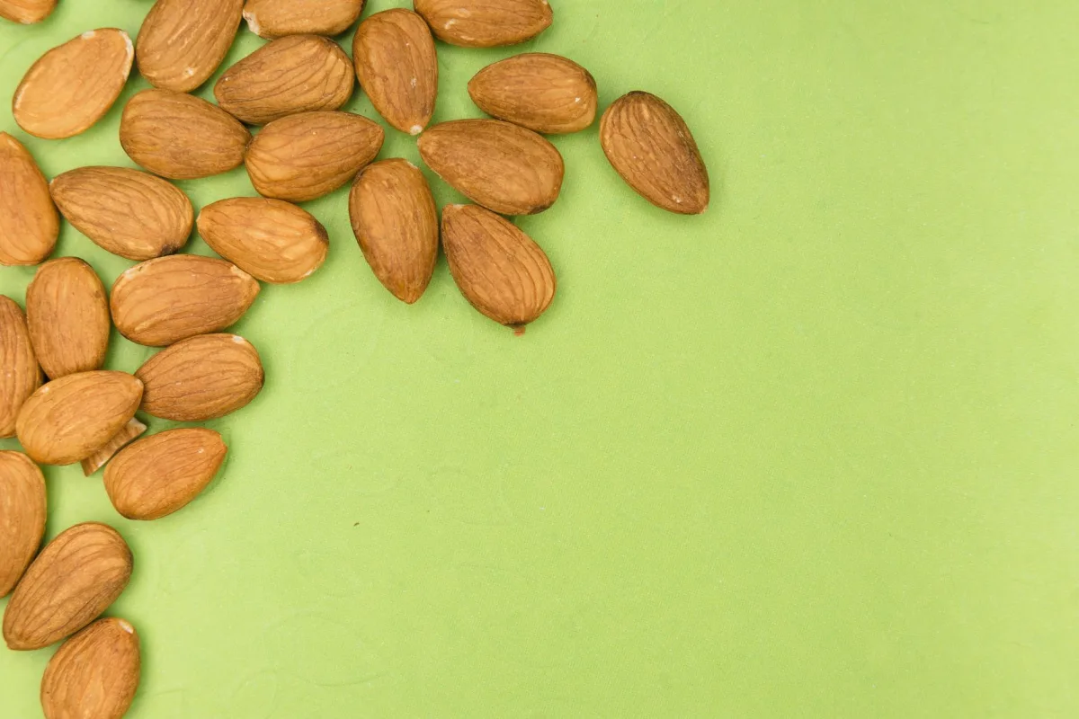 Cinq coupelles en céramique présentant des amandes entières, effilées, en poudre, en purée et un verre de lait d'amande