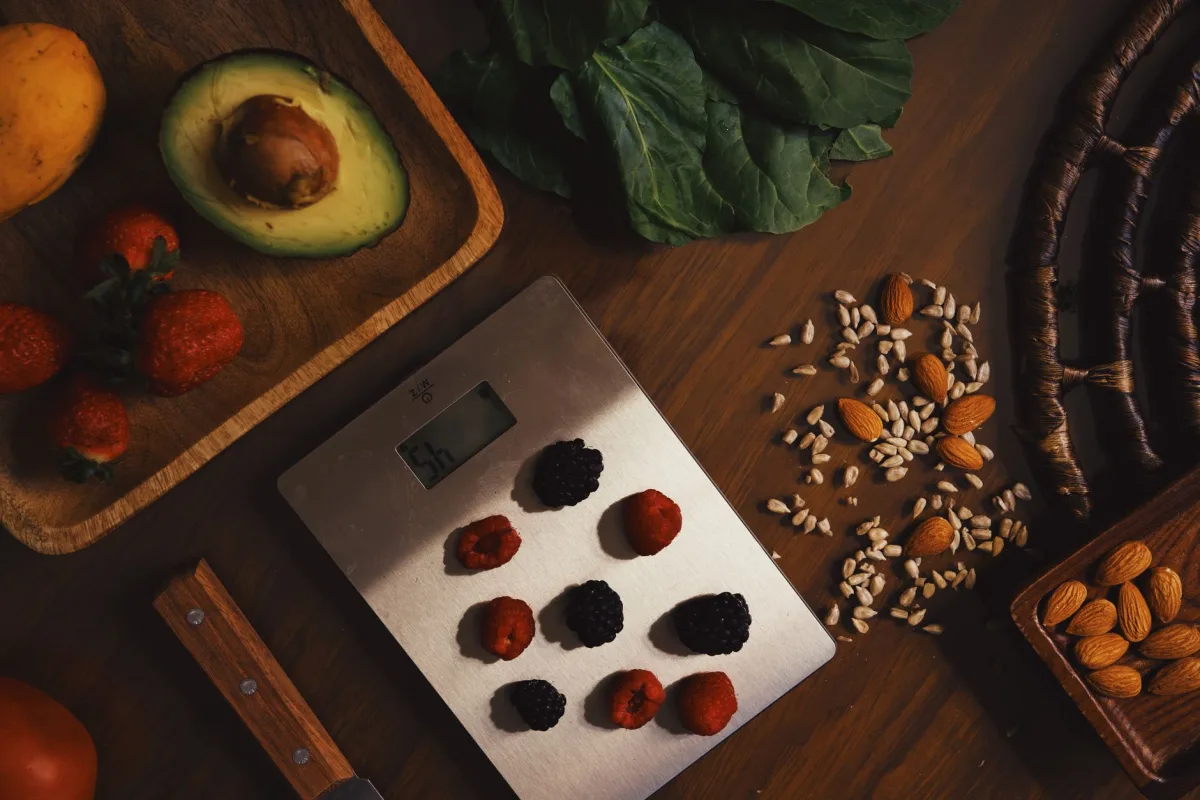 Balance de cuisine posée sur un plan de travail clair, avec une coupelle en céramique contenant des amandes pesées