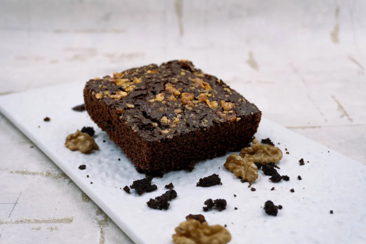 Part de brownie aux noix coupée, cœur fondant et cerneaux visibles