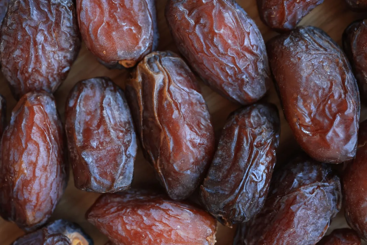 Dattes Medjool entières dans une coupelle en céramique, à côté de dattes Deglet Nour plus fines