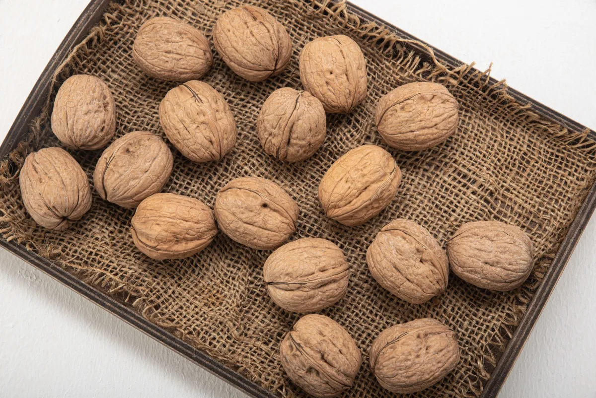 Cerneaux de noix pesés sur une balance de cuisine à côté d'un pot de miel