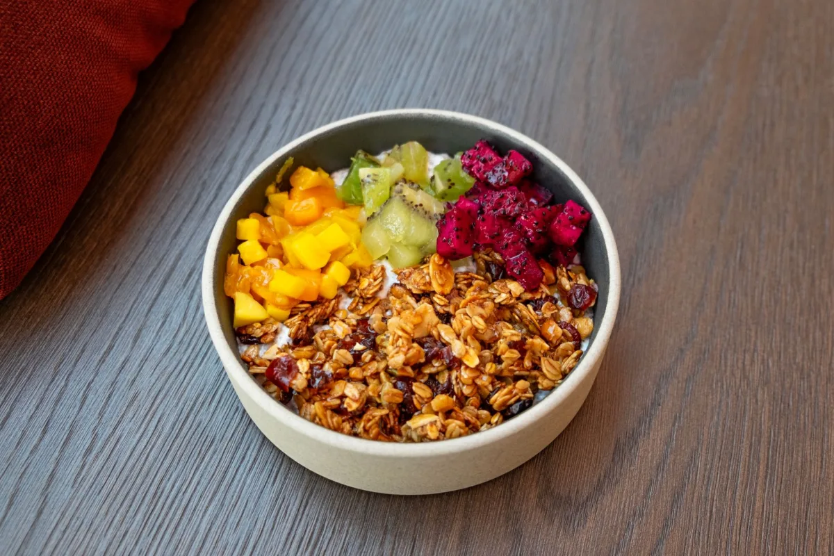 Trente grammes d'amandes entières pesées sur une balance de cuisine à côté d'un bocal de granola